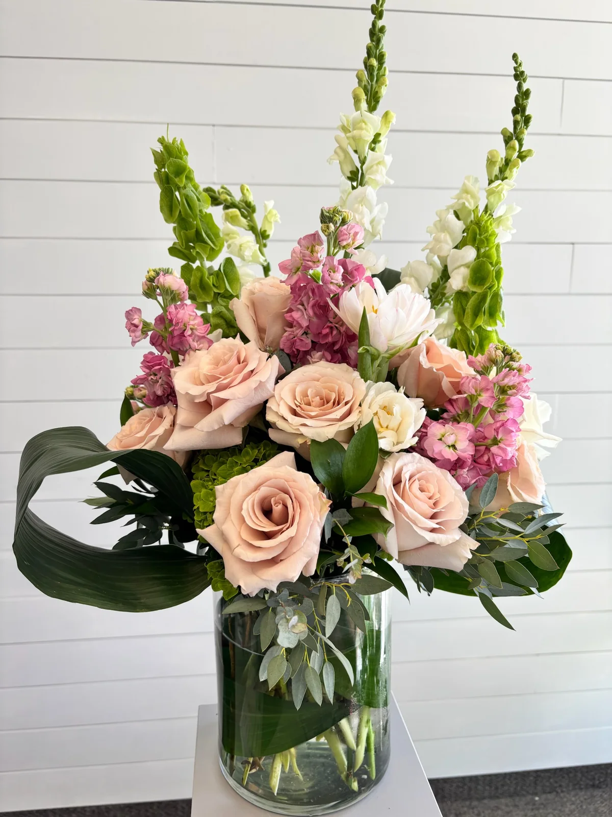 Large custom funeral flower arrangement in blush and soft seasonal tones